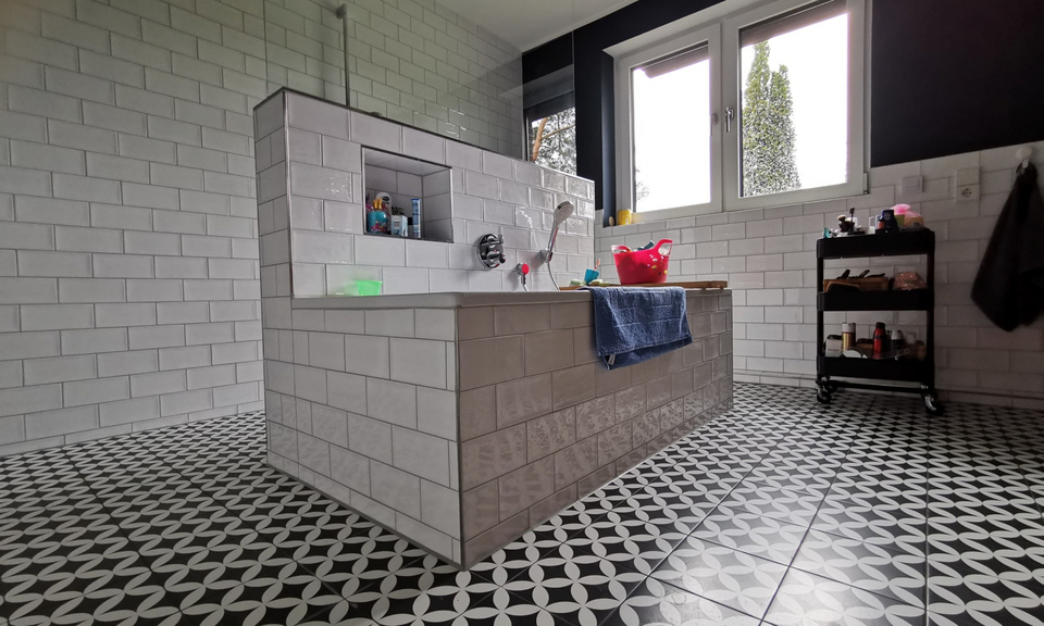 Modernes Badezimmer mit gemustertem Fliesenboden und freistehender Badewanne in der Raummitte