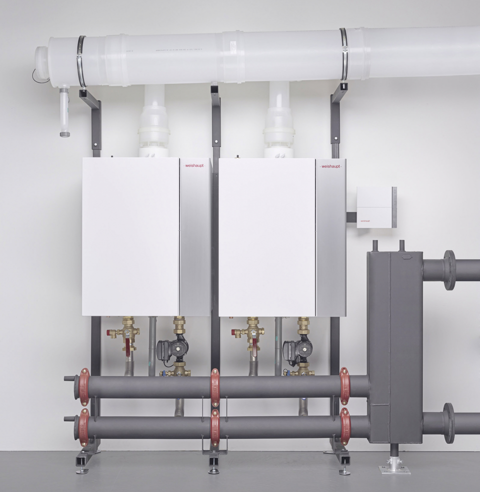 Zwei Gasbrennwertgeräte in einer professionellen Heizzentrale mit Verteilerrohr, Pumpen und Armaturen.